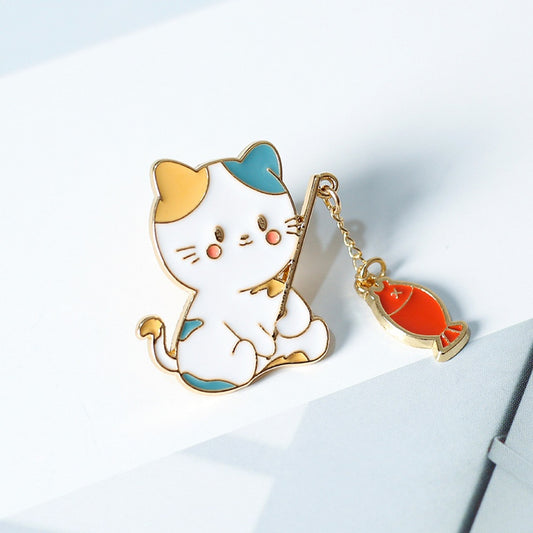 un pin's en forme de chat qui est en train de pêcher. Il a une canne à pêche composée d'une chainette. Au bout se trouve un poisson !