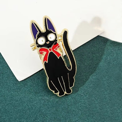 un pin's représentant Jiji, le chat noir de Kiki la petite sorcière. Avec son noeud rouge et ses oreilles violettes, il est un personnage plein de charisme et de charme.