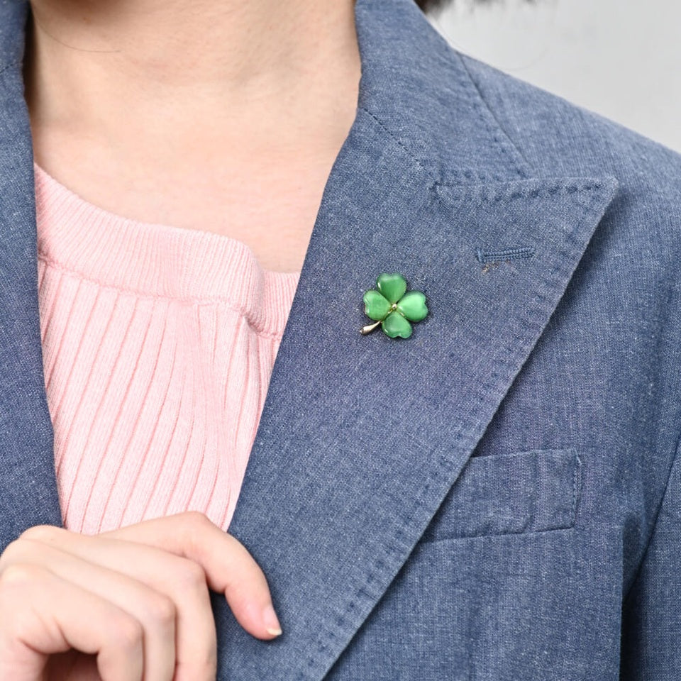 un pin's doré en forme de trèfle vert à 4 feuilles. Les feuilles sont en résine brillantes. Symbole de chance. Look élégant et mignon à la fois.