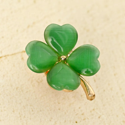 un pin's doré en forme de trèfle vert à 4 feuilles. Les feuilles sont en résine brillantes. Symbole de chance. Look élégant et mignon à la fois.