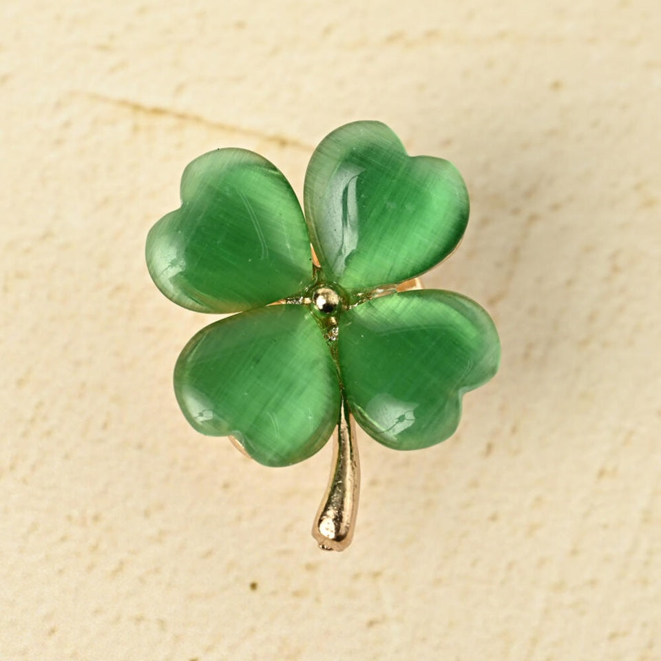 un pin's doré en forme de trèfle vert à 4 feuilles. Les feuilles sont en résine brillantes. Symbole de chance. Look élégant et mignon à la fois.