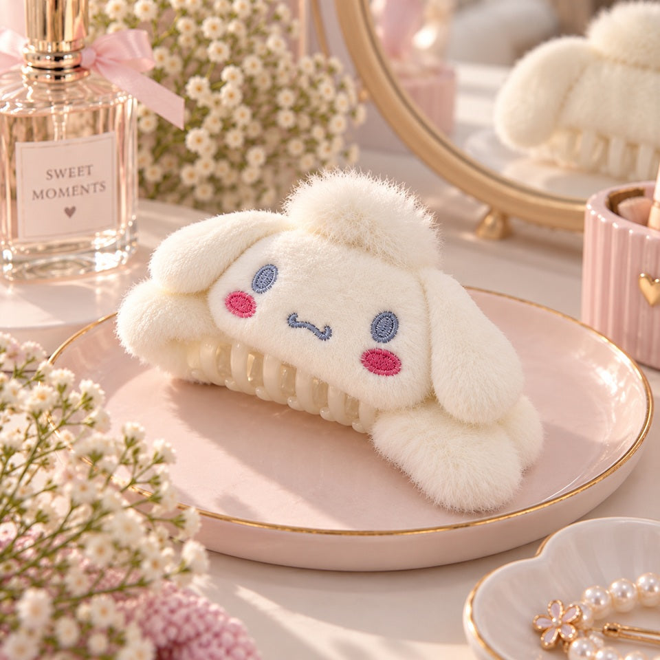 Pince à cheveux kawaii en peluche blanche avec oreilles tombantes et détails brodés roses et bleus, présentée dans un décor féminin pastel