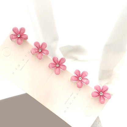 un lot de 5 pinces à cheveux en forme de fleurs de sakura roses pailletées. Au coeur des fleurs, se trouve un strass brillant. Parfaites pour un look printanier, romantique et adorable.