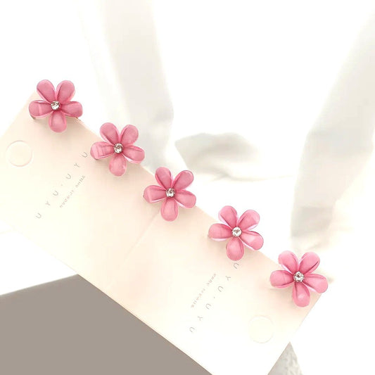 un lot de 5 pinces à cheveux en forme de fleurs de sakura roses pailletées. Au coeur des fleurs, se trouve un strass brillant. Parfaites pour un look printanier, romantique et adorable.