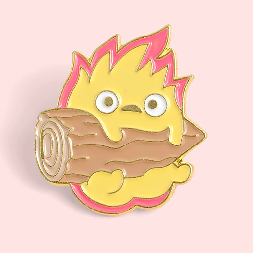 un adorable pin's représentant Calcifer le personnage du château ambulant tenant une buche de bois sur un fond rose. Idéal à collectionner.