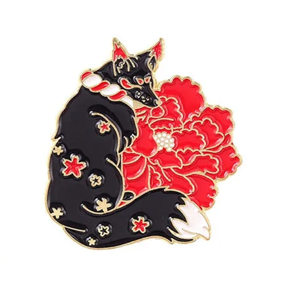un pin's en forme de kitsune noir dont la fourrure est ornée de fleurs de sakura rouges. Une grosse fleur rouge se trouve derrière le renard. L'ensemble est poétique, rempli de symbole