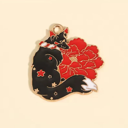 un pin's en forme de kitsune noir dont la fourrure est ornée de fleurs de sakura rouges. Une grosse fleur rouge se trouve derrière le renard. L'ensemble est poétique, rempli de symbole