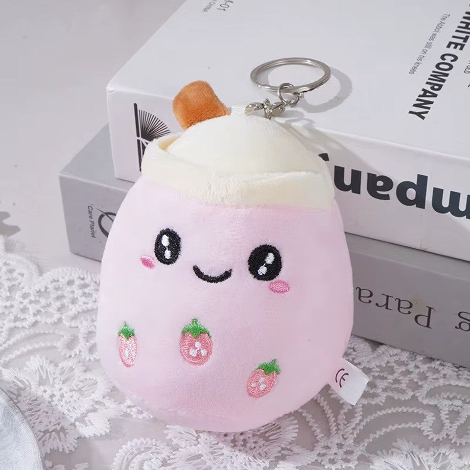 un adorable porte-clé bubble tea rose tout doux. Il a une expression kawaii et de petites fraises roses brodées sur son ventre.