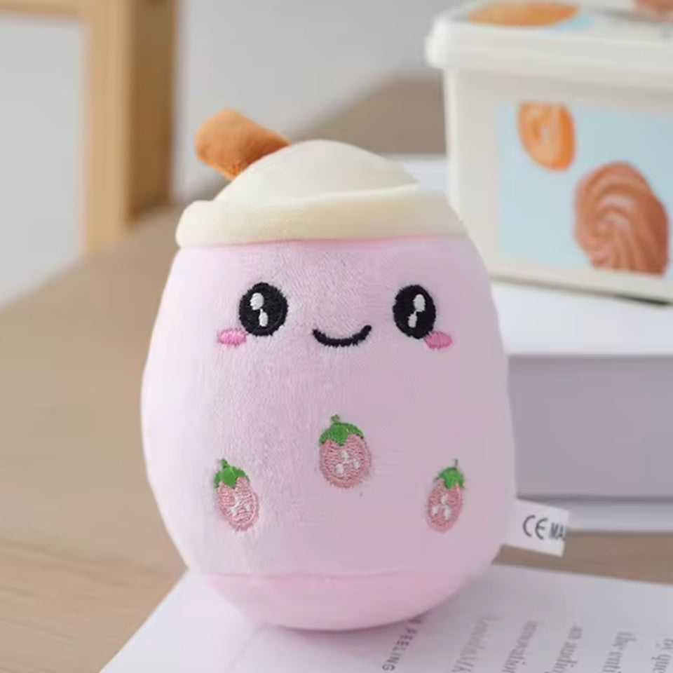 un adorable porte-clé bubble tea rose tout doux. Il a une expression kawaii et de petites fraises roses brodées sur son ventre.
