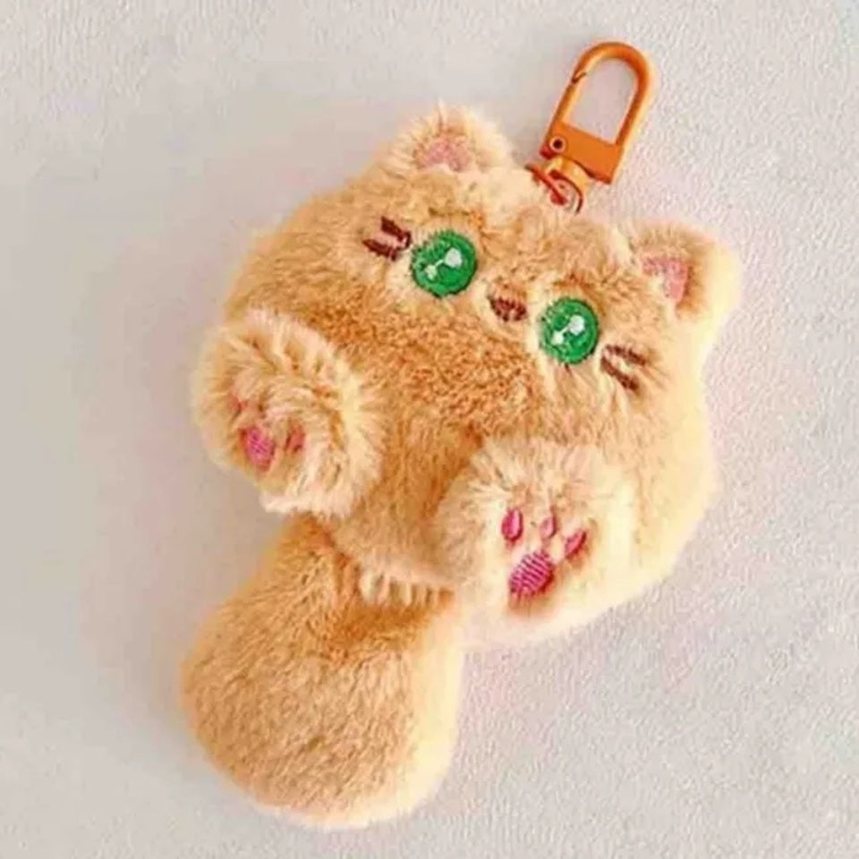 un porte-clé en forme de chat brun avec de grands yeux verts. Tout en fourrure, il ressemble à une petite boule de poil qu'on a envie de câliner. Tout doux et trop mignon !