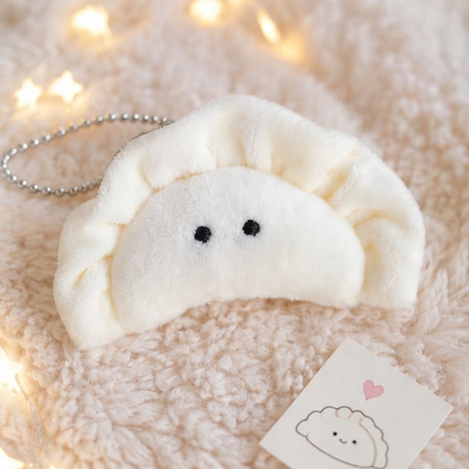 Porte-clés peluche kawaii en forme de gyoza  mignon blanc crème est présenté sur un tapis beige. L'ambiance douce et chaleureuse est agrémentée d'une guirlande lumineuse et d'éléments décoratifs inspirés de l'univers kawaii japonais. Idéal pour personnaliser un sac, un sac à dos ou un trousseau de clés.