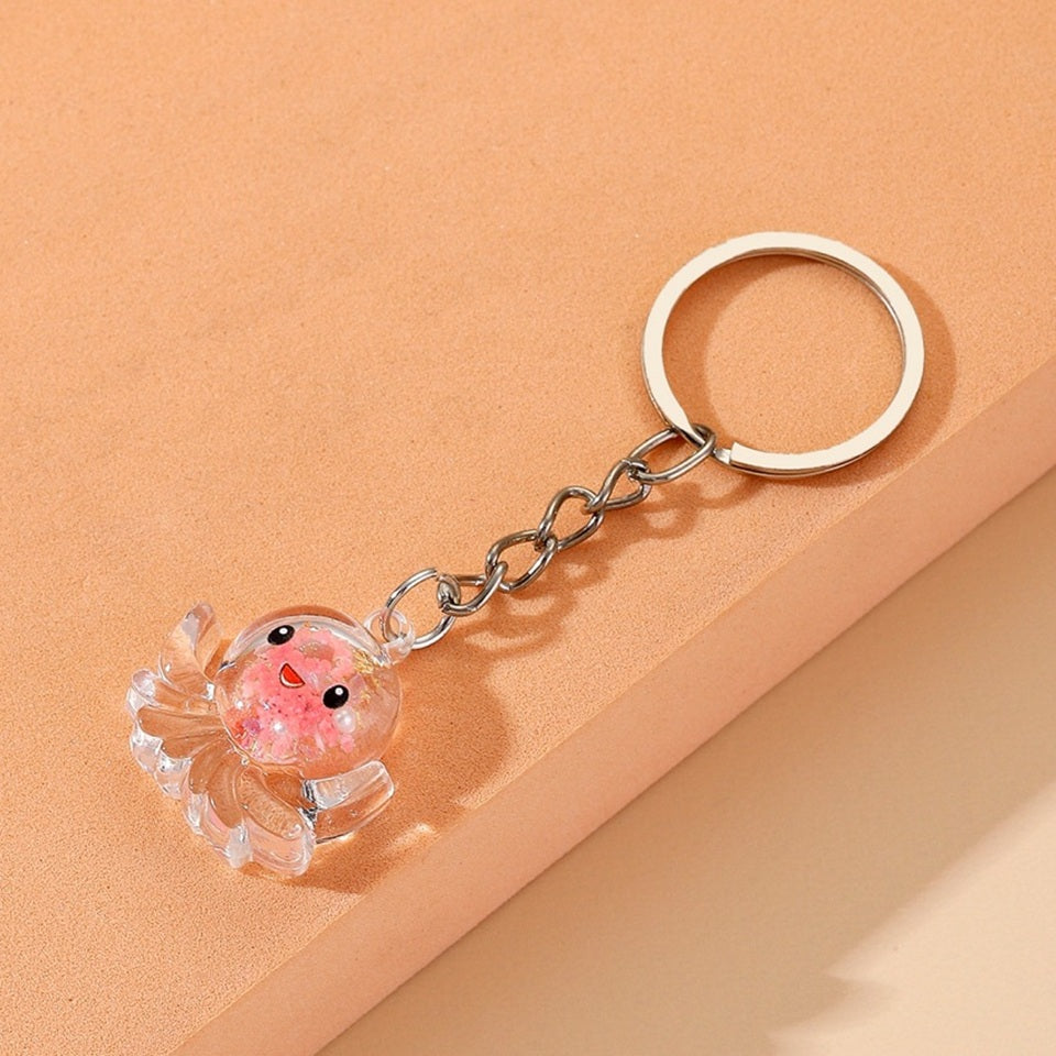 un porte-clé en acrylique en forme d'octopus trop mignon. Il renferme des paillettes roses et dorées et a une expression kawaii trop mignonne !
