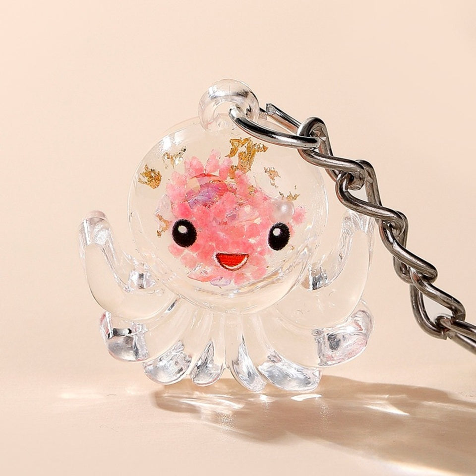 un porte-clé en acrylique en forme d'octopus trop mignon. Il renferme des paillettes roses et dorées et a une expression kawaii trop mignonne !