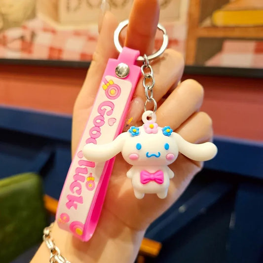 un adorable porte-clé représentant Cinnamoroll qui porte des fleurs sur la tête et un joli noeud rose