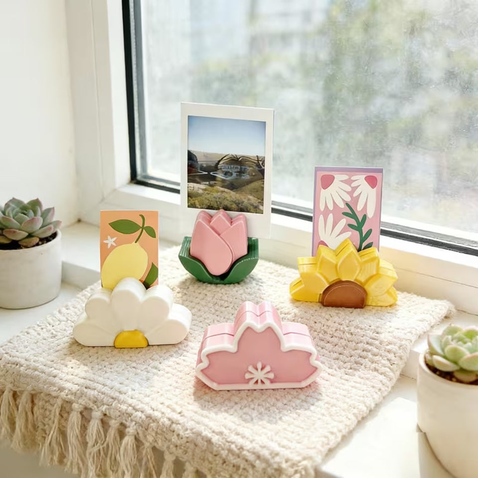 Porte-photos floraux colorés en forme de tulipe rose, tournesol jaune, marguerite blanche et fleur de cerisier, présentés avec photos et cartes dans une décoration kawaii lumineuse.