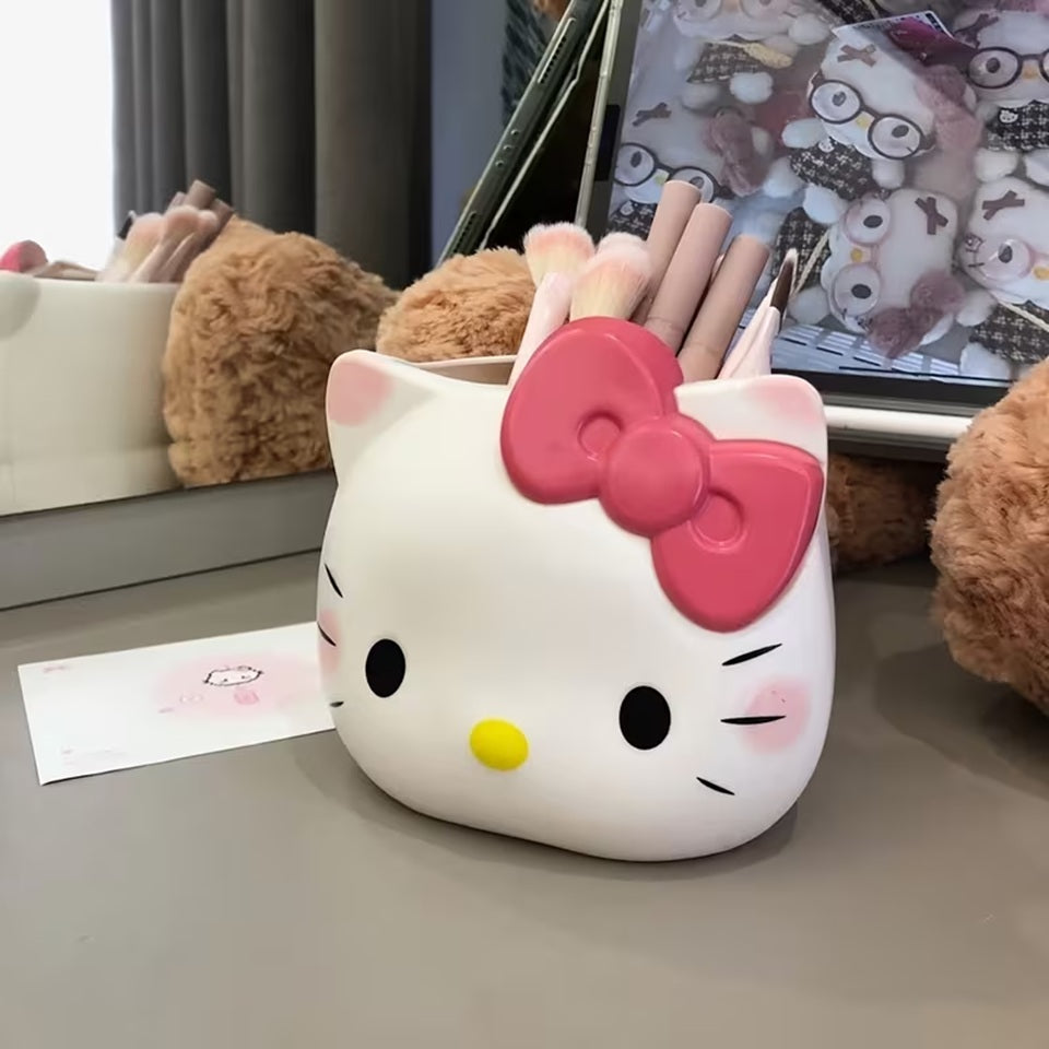 Un pot à crayons en forme d'Hello Kitty, posé sur une table grise, entouré de divers accessoires mignons. Du maquillage est rangé dans le pot.