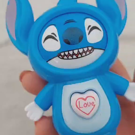 un porte-clés en forme de Stitch de Lilo et Stitch. Il a un petit coeur sur le ventre qui permet de changer son expression de visage. Tant espiègle, tnatot amoureux, il est trop adorable !