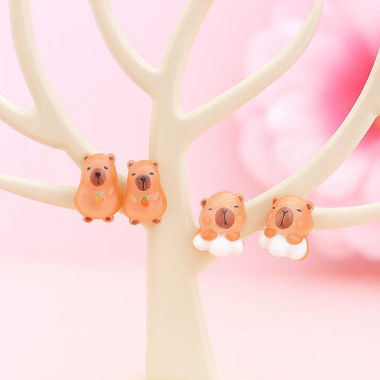 des puces d'oreilles en forme de capybara tout mignon, l'un est un nuage et l'autre tient une pomme rouge