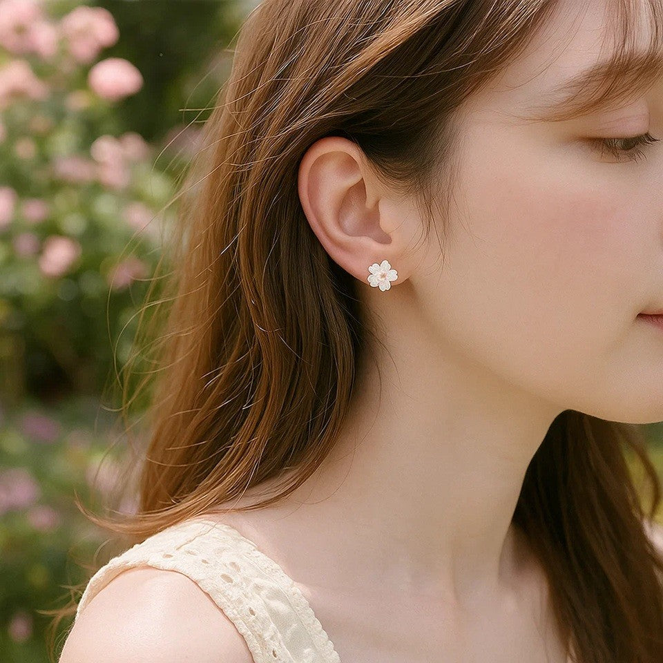 Une paire de puces d'oreilles argentées  délicates en forme de fleurs de cerisier dont le coeur est un petit strass brillant. Leur coloris rosé est délicate