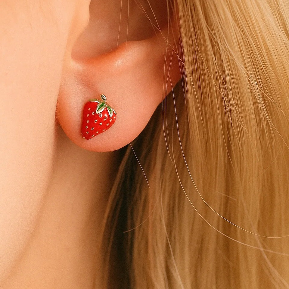 une paire de puces d'oreilles toutes mignonnes en forme de fraises bien rouges et de détails dorés