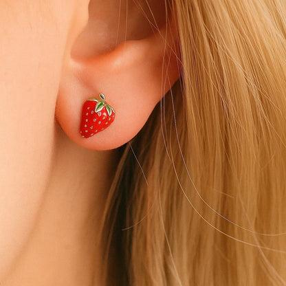 une paire de puces d'oreilles toutes mignonnes en forme de fraises bien rouges et de détails dorés