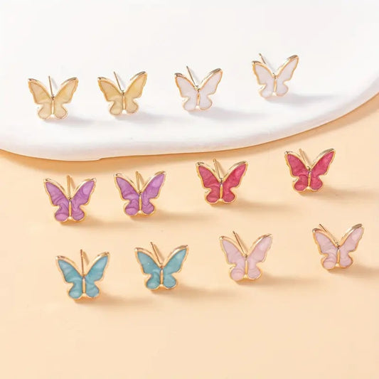 une paire de puces d'oreilles minimaliste en forme de papillons colorés et dorées : aune, blanc, violet, bleu, rose et fuschia