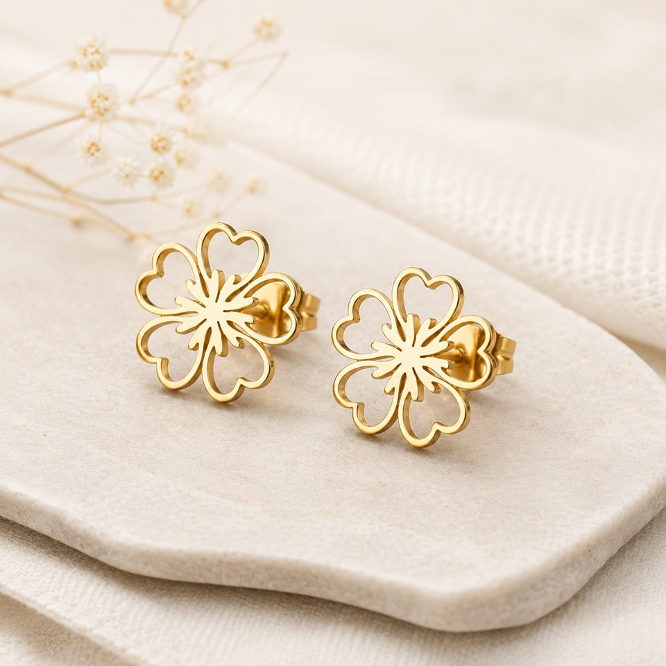 une paire de puces d'oreilles dorées en forme de fleur de sakura dans un style minimaliste et mignon