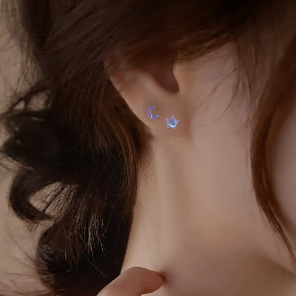 des puces d'oreilles asymétriques : un côté en forme de lune, un côté en forme d'étoile. Design minimaliste et coloré