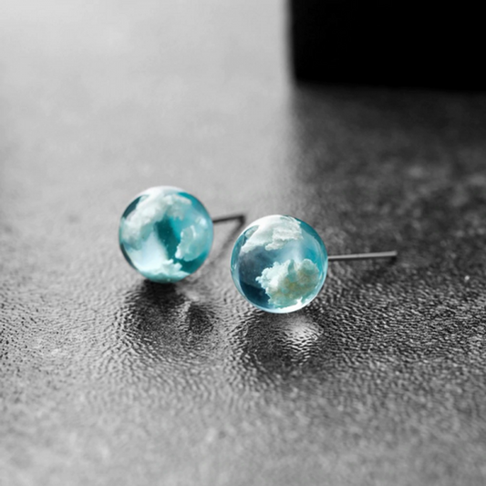 des boucles d'oreilles rondes en verre transparent et bleu. A l'intérieur, on peut voir comme des nuages blancs. On dirait que l'on a capturé un bout de ciel.