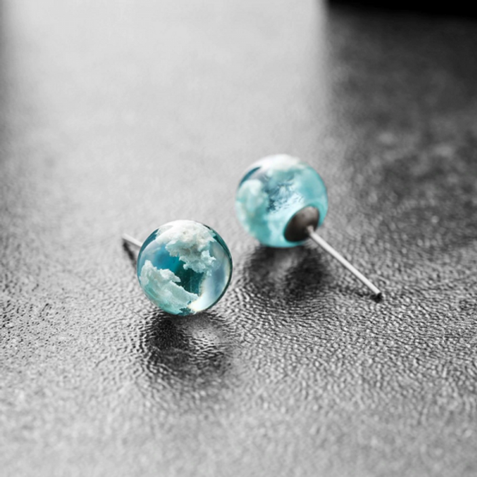des boucles d'oreilles rondes en verre transparent et bleu. A l'intérieur, on peut voir comme des nuages blancs. On dirait que l'on a capturé un bout de ciel.