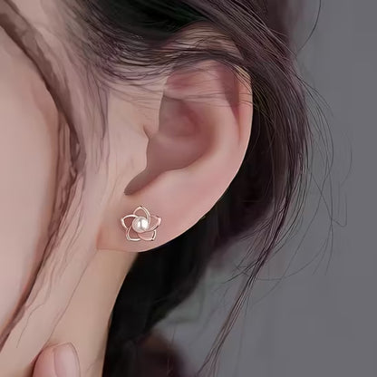 des puces d'oreilles en forme de petites fleurs dorées dont le coeur est une perle blanche. Le style est minimaliste et élégant.