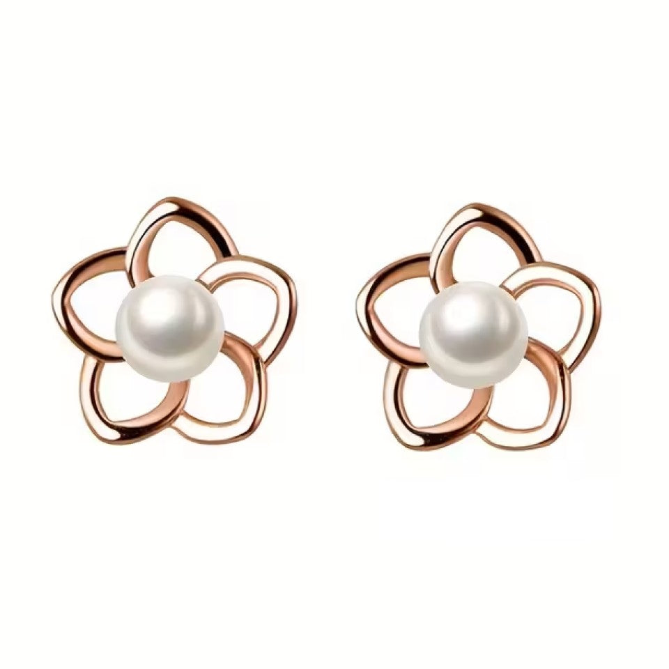 des puces d'oreilles en forme de petites fleurs dorées dont le coeur est une perle blanche. Le style est minimaliste et élégant.