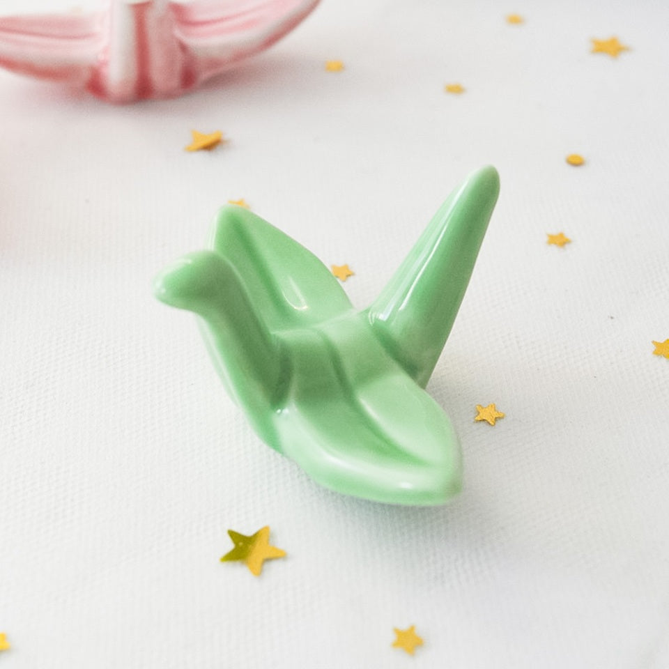 des repose baguettes en forme de grue japonaise colorée : rose, orange, bleu et vert. En céramique, elles sont résistantes et durables et ajoutent une touche authentique du Japon et d'élégance sur votre table.