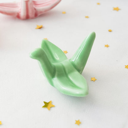 des repose baguettes en forme de grue japonaise colorée : rose, orange, bleu et vert. En céramique, elles sont résistantes et durables et ajoutent une touche authentique du Japon et d'élégance sur votre table.