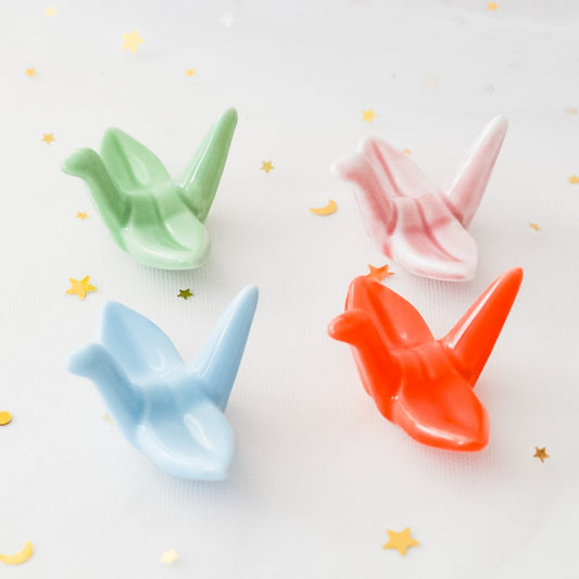 des repose baguettes en forme de grue japonaise colorée : rose, orange, bleu et vert. En céramique, elles sont résistantes et durables et ajoutent une touche authentique du Japon et d'élégance sur votre table.