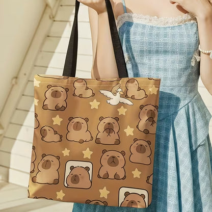 un sac fourre-tout marron au design de capybara et d'étoiles trop mignons. Il est tenue dans la main d'une femme habillée d'une robe bleue. Ambiance ensoleillée et mignonne pour un look adorable