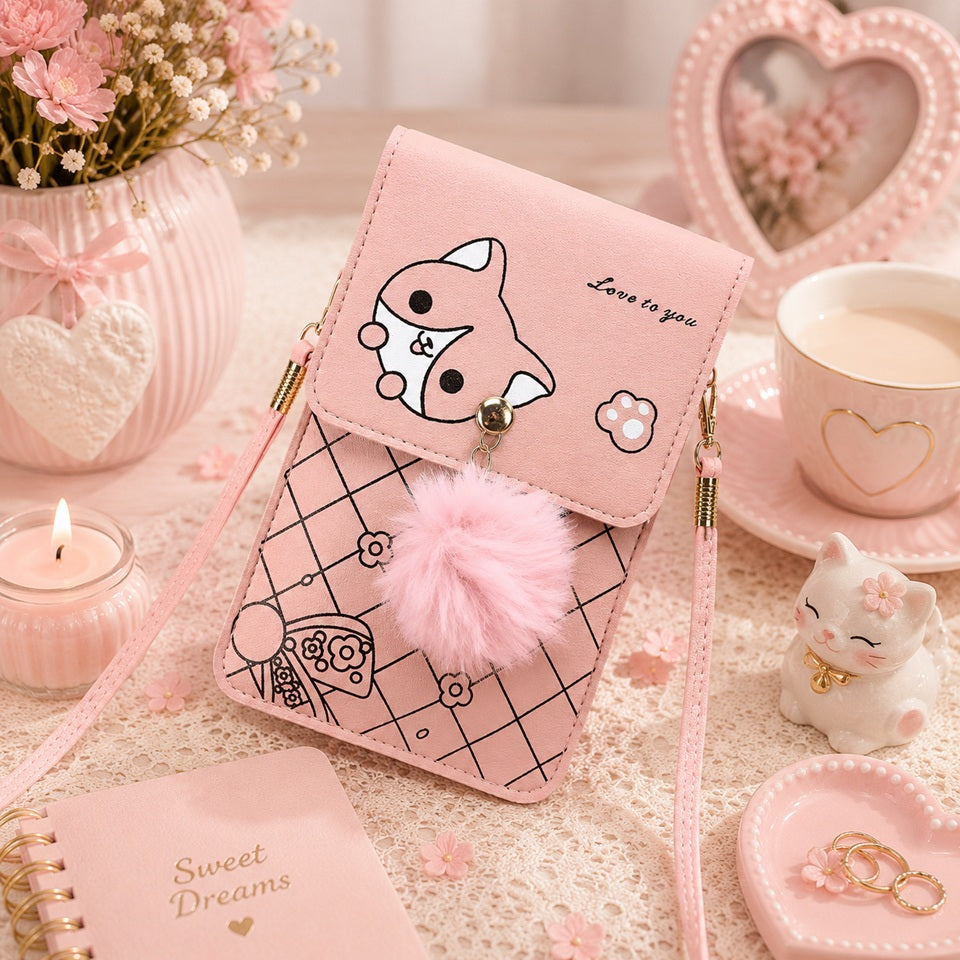 Sacoche téléphone rose kawaii avec motif chat, pompon en fausse fourrure et bandoulière, présentée dans un décor romantique pastel avec fleurs, bougie, tasse, figurine de chat et accessoires décoratifs. Petit sac à bandoulière pour femme, pratique et tendance.