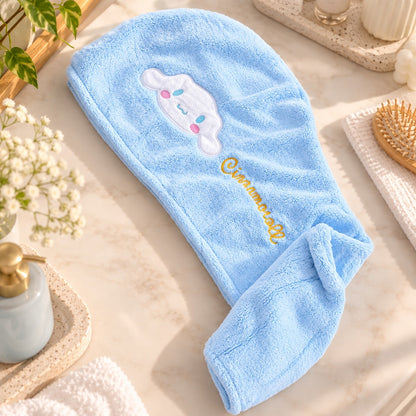 Serviette pour cheveux Cinnamoroll bleu clair en tissu doux, posée à plat dans un joli décor de salle de bain lumineux avec accessoires de soin et fleurs.