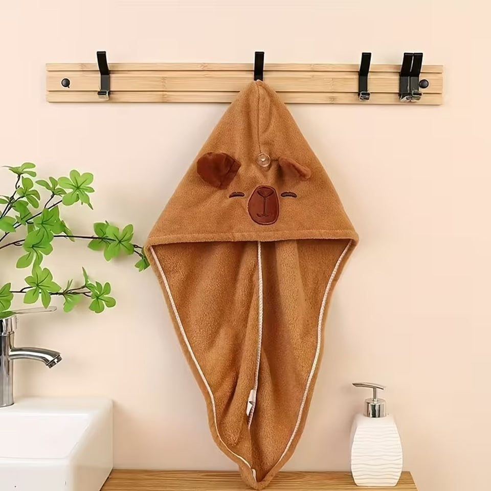 une serviette pour cheveux capybara doté d'oreilles toutes mignonnes. Avec son visage brodé et son sourire charmeur, ce capybara est utile et pratique pour maintenir et sécher les cheveux après la douche ou le bain.