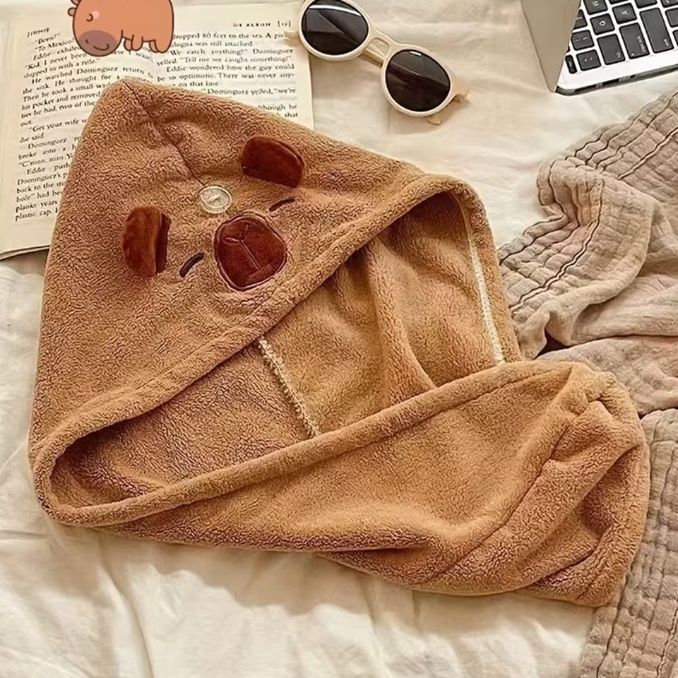 une serviette pour cheveux capybara doté d'oreilles toutes mignonnes. Avec son visage brodé et son sourire charmeur, ce capybara est utile et pratique pour maintenir et sécher les cheveux après la douche ou le bain.