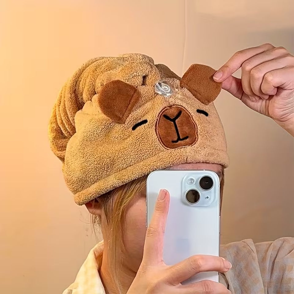 une serviette pour cheveux capybara doté d'oreilles toutes mignonnes. Avec son visage brodé et son sourire charmeur, ce capybara est utile et pratique pour maintenir et sécher les cheveux après la douche ou le bain.