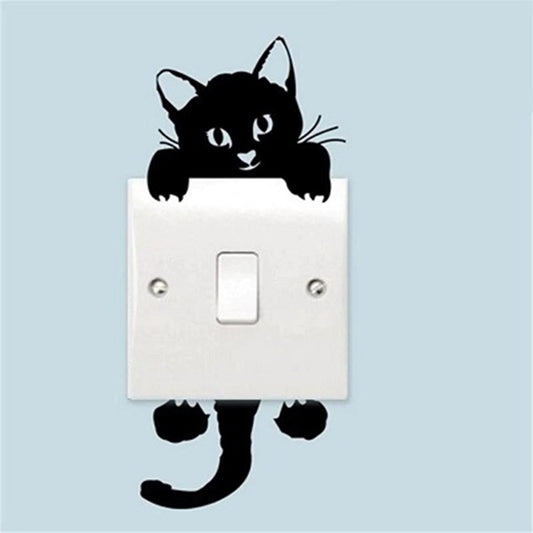 un sticker mural d'un chat noir très mignon et espiègle Il est divisé en deux parties : une supérieure à coller au-dessus d'un interrupteur et la partie inférieure en dessous. Il ajoute une touche mignonne à une pièce.