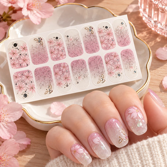 Stickers pour ongles rose et blanc aux fleurs de sakura, paillettes et strass, présentés avec une manucure florale élégante et romantique.
