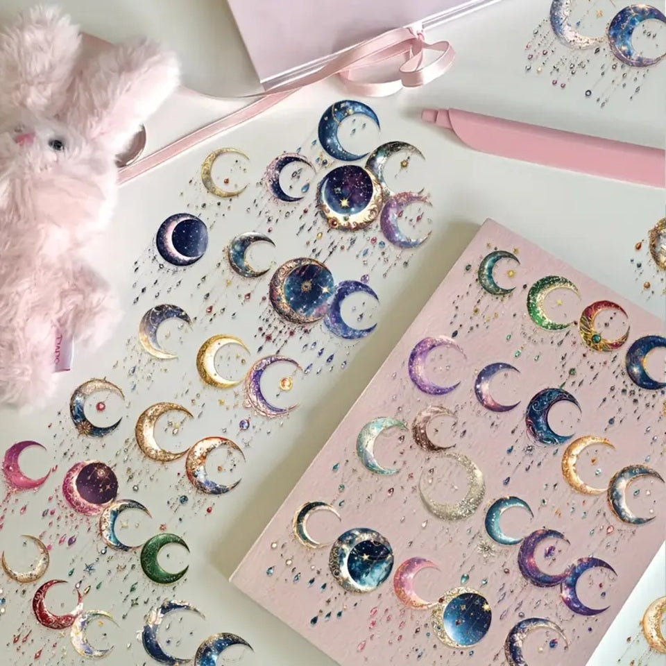 des stickers en forme de lune coloré et décorées de détails dorés, des pampilles et strass colorés et brillantes y sont suspendus