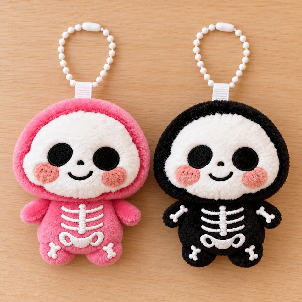 Deux porte-clés peluches kawaii en forme de petits squelettes roses et noirs, au toucher doux, avec visages souriants, joues roses et détails brodés blancs. Adorables accessoires de sac présentés à plat sur un fond en bois clair.
