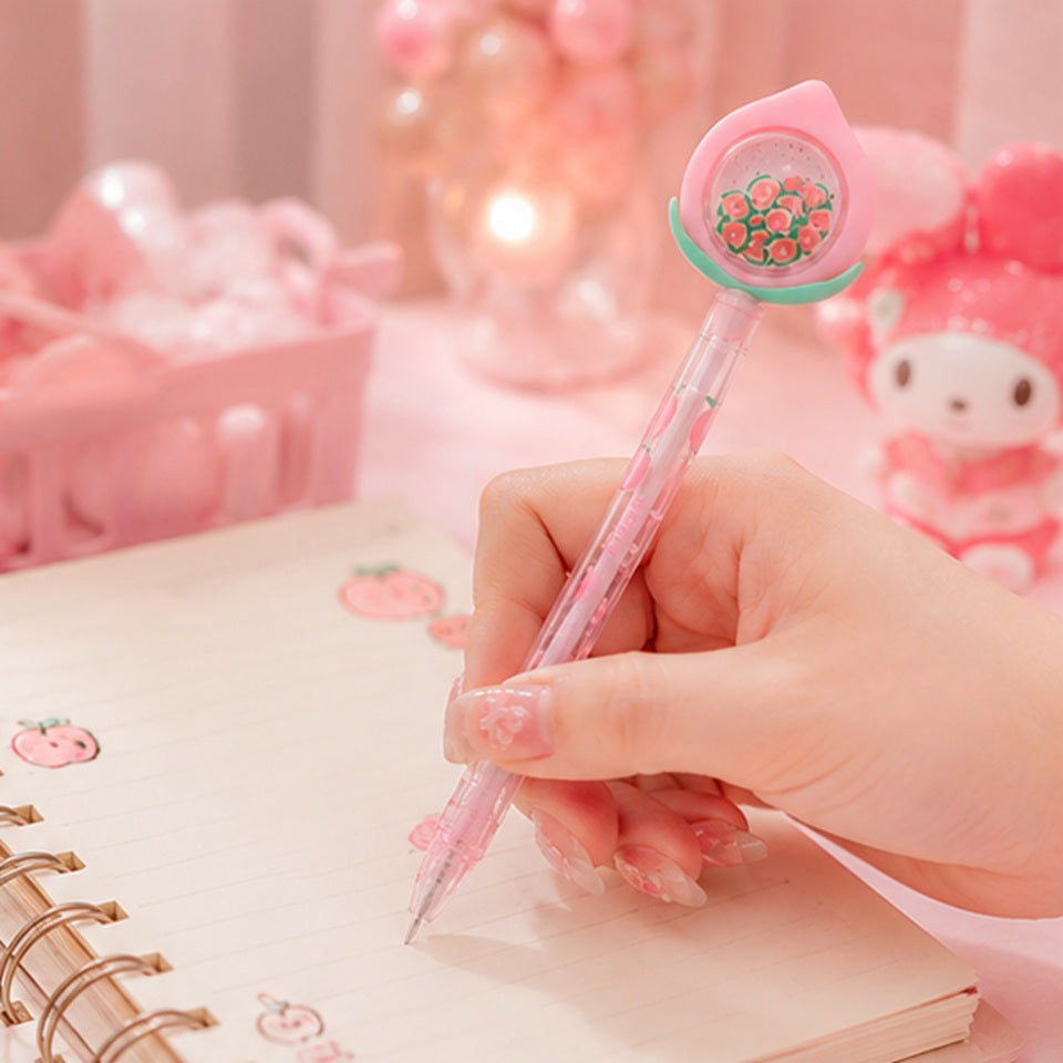 Main écrivant dans un carnet avec un stylo pêche kawaii rose au design fruité adorable ✨ Stylo gel transparent décoré de petites pêches avec embout pastel, parfait pour ajouter une touche douce, mignonne et créative à son journal ou son bureau. Ambiance cosy rose inspirée de la papeterie japonaise kawaii.
