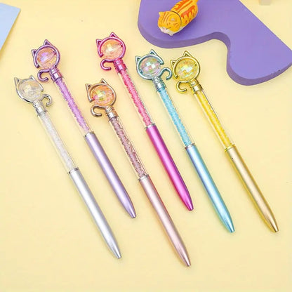 des stylos funs et originaux dont le corps renferme des cristaux colorés et brillants :violet, argenté, bleu, rose, jaune et doré. Au bout du stylo se trouve une boule que l'on peut faire tourner et autour de laquelle est enroulé une queue de chat  et qui ferme des oreilles de chat également
