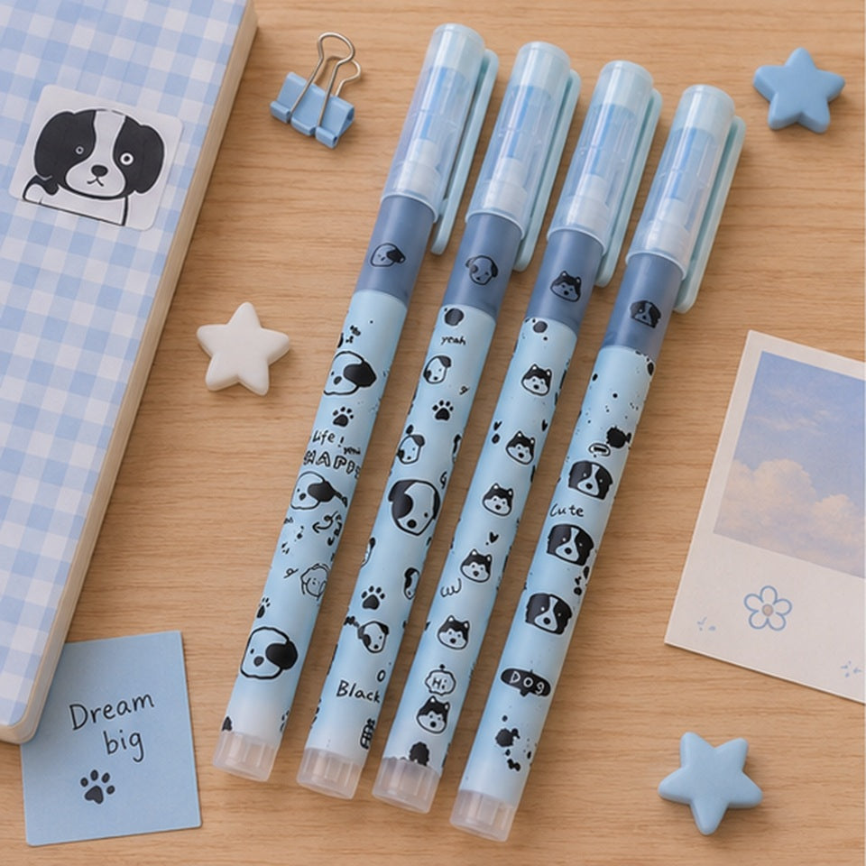 un lot de 4 stylos de couleur bleu au motif d'adorables chiens noirs posés sur une table en bois brun. Ils sont entourés d'articles de papeterie divers.