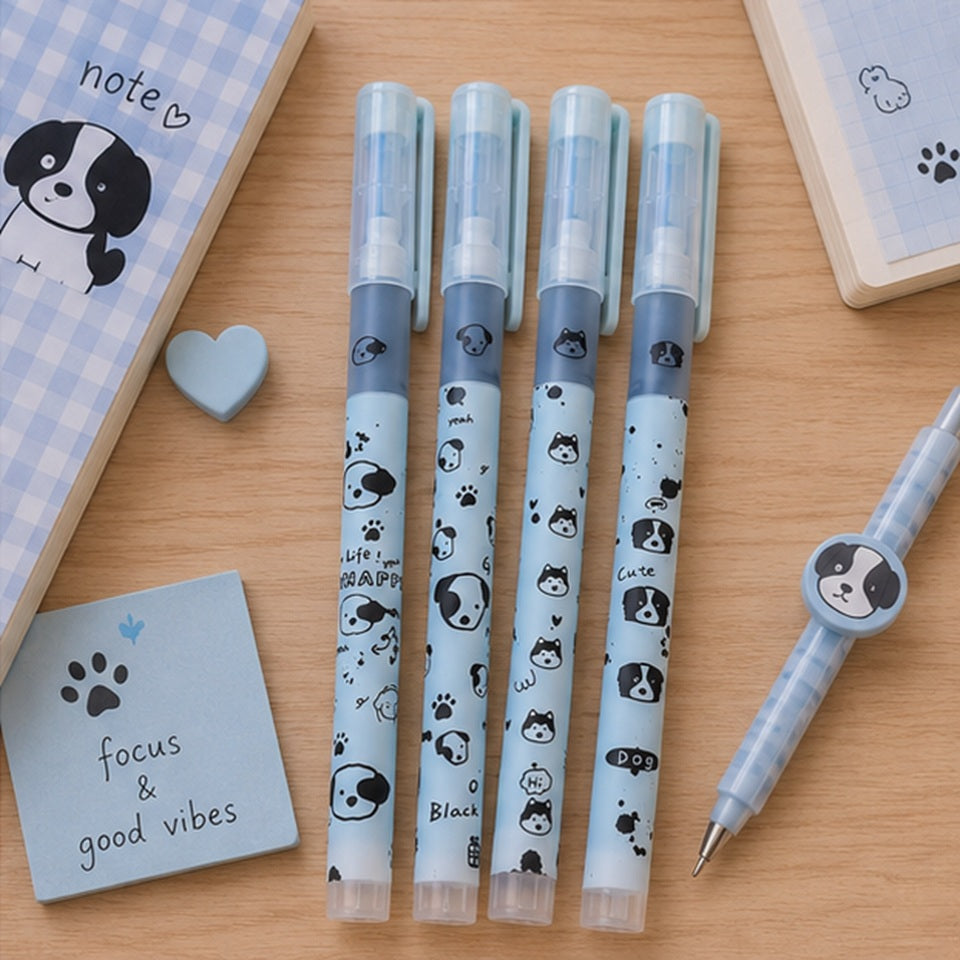un lot de 4 stylos de couleur bleu au motif d'adorables chiens noirs posés sur une table en bois brun.  Ambiance scolaire et mignonne