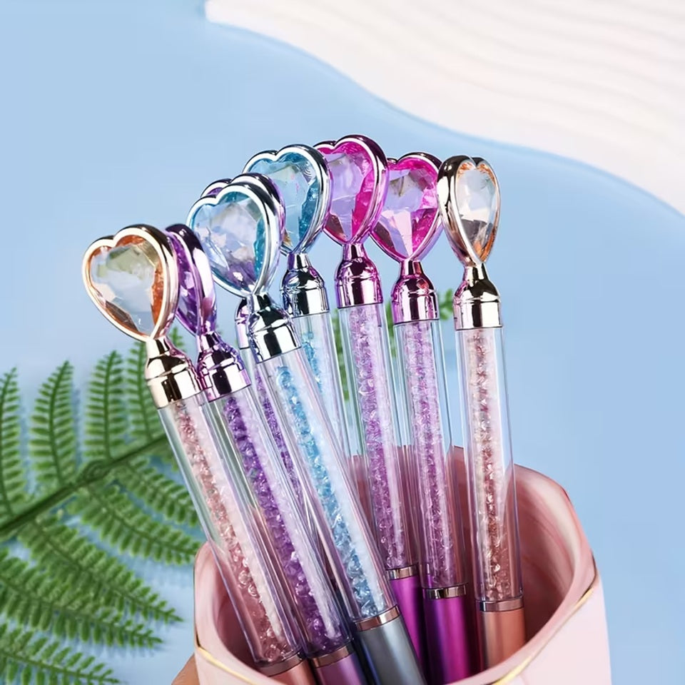 des stylos coeurs colorés dont le corps transparent renferme des strass brillants. Au but du stylo se trouve un joli coeur coloré comme s'il avait été taillé dans un diamant. L'ensemble est poétique et élégant.